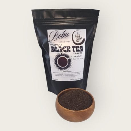 A package of Boba Licious Black Tea Leaves with a wooden bowl of tea leaves in front, isolated on a white background. The packaging displays the product name and ingredients.